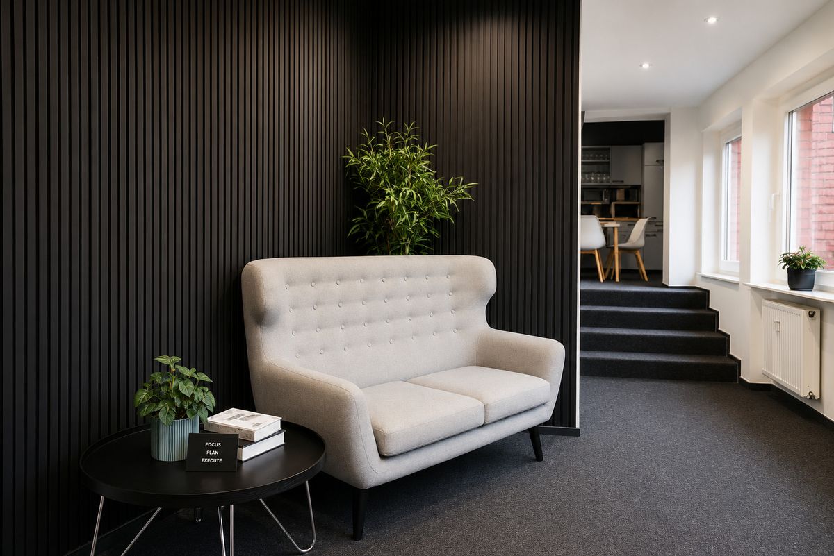 Lounge mit Sofa vor dunkler Holzwand im Gründer Hub Barmbek